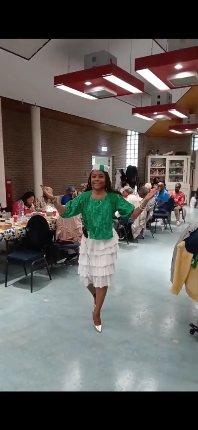 Sharynné Martijn treedt op in een groen-witte outfit tijdens een culturele bijeenkomst